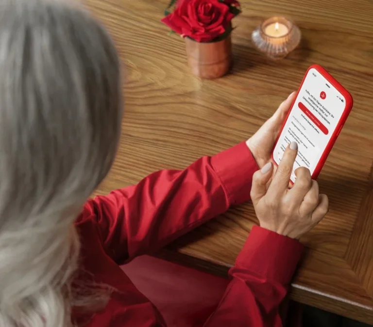 Frau bedient Smartphone am Tisch, Signia Pure Charge&Go MaX, Göldi Hörberatung